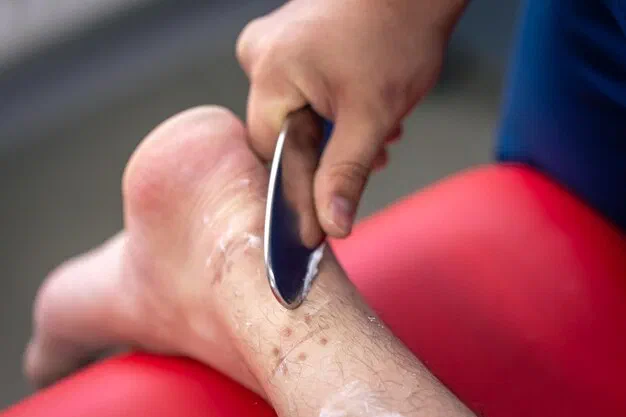 Physical therapist performing IASTM with a smooth instrument on a patient's forearm at Root Therapy and Wellness in Bozeman, Montana